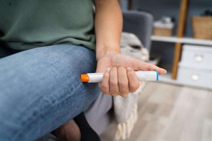 A woman injecting epinephrine using an auto-injector syringe