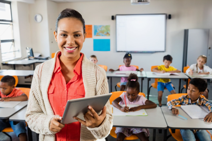 Teacher standing in front of her class holding a tablet device